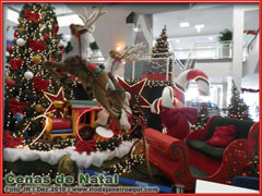 Decora&ccedil;&atilde;o de natal com tren&oacute; de papai noel puxado por renas e cercado de pinheiros e luzes cintilantes