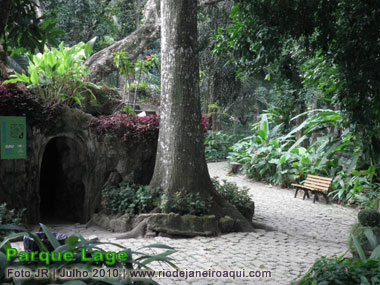Entrada da casa do aquario do Parque Lage ao lado de uma viela rodeada de uma floresta de árvores e jardins romanticos